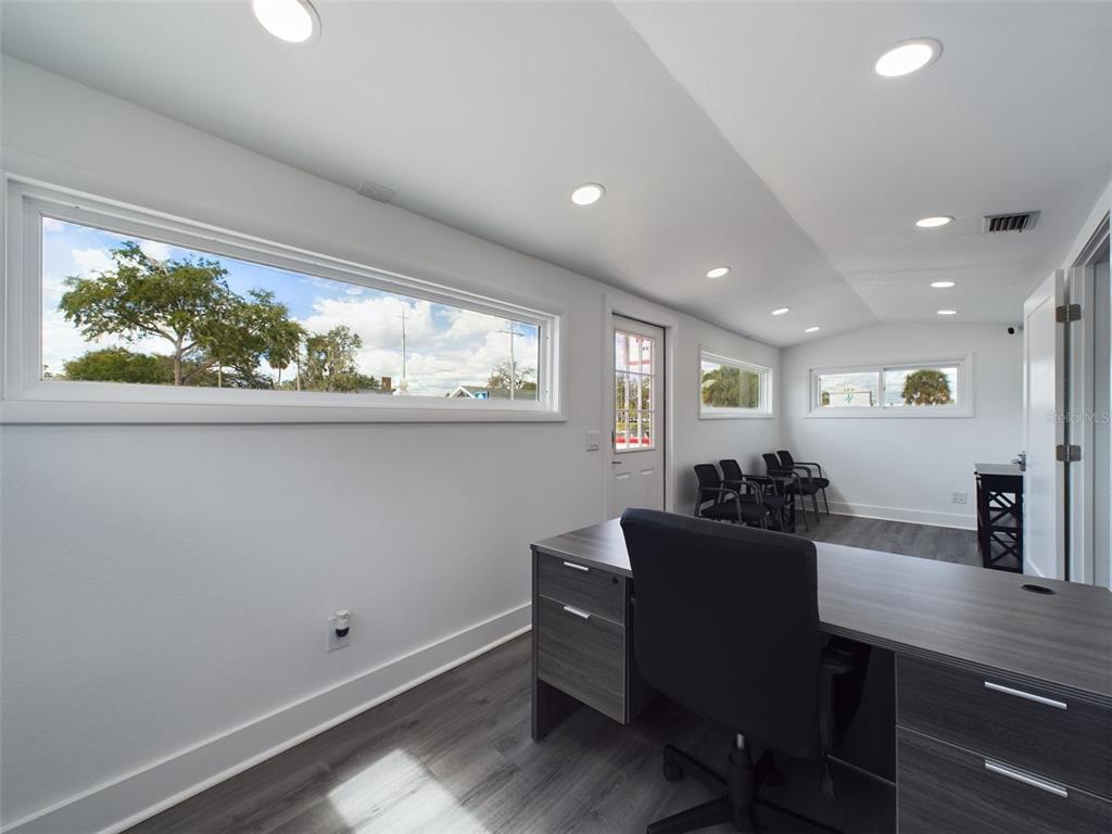 A modern office space features a dark wood desk, gray flooring, and multiple horizontal windows — 334 1ST STREET S, WINTER HAVEN, FL
