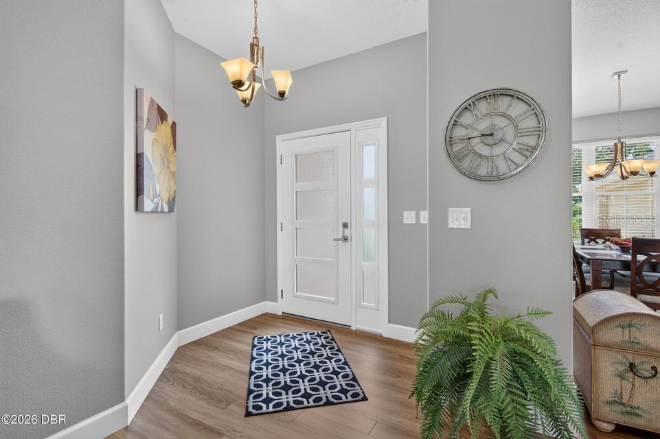 An entryway features gray walls, wood-look flooring, a white front door, and a wall clock — 105 OPAL HILL CIRCLE, DAYTONA BEACH, FL