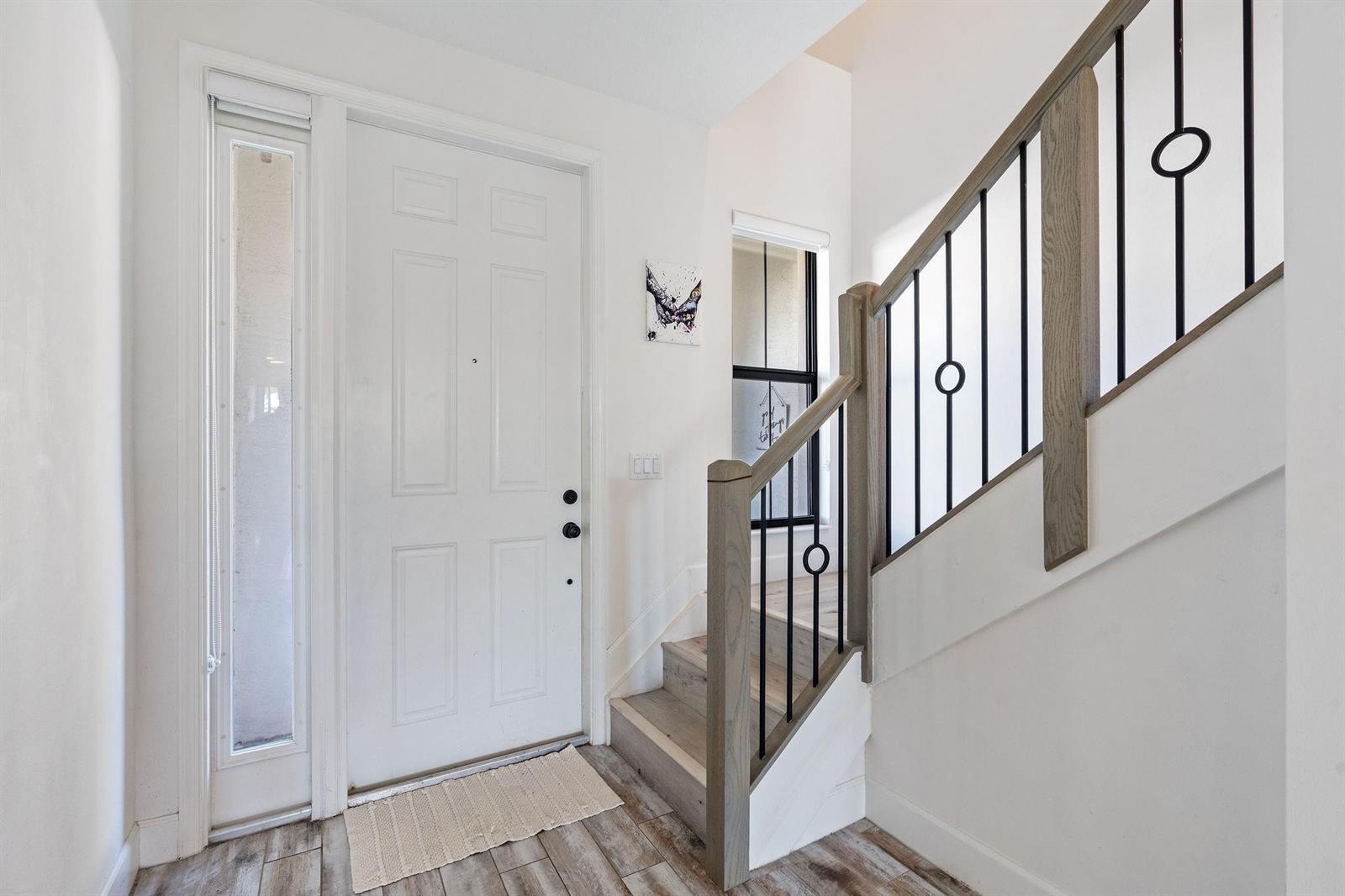 An entryway features a white front door, wood-look flooring, and a staircase with metal railings — 12512 NW 32 Manor # 3, Sunrise FL 33323, SUNRISE, FL