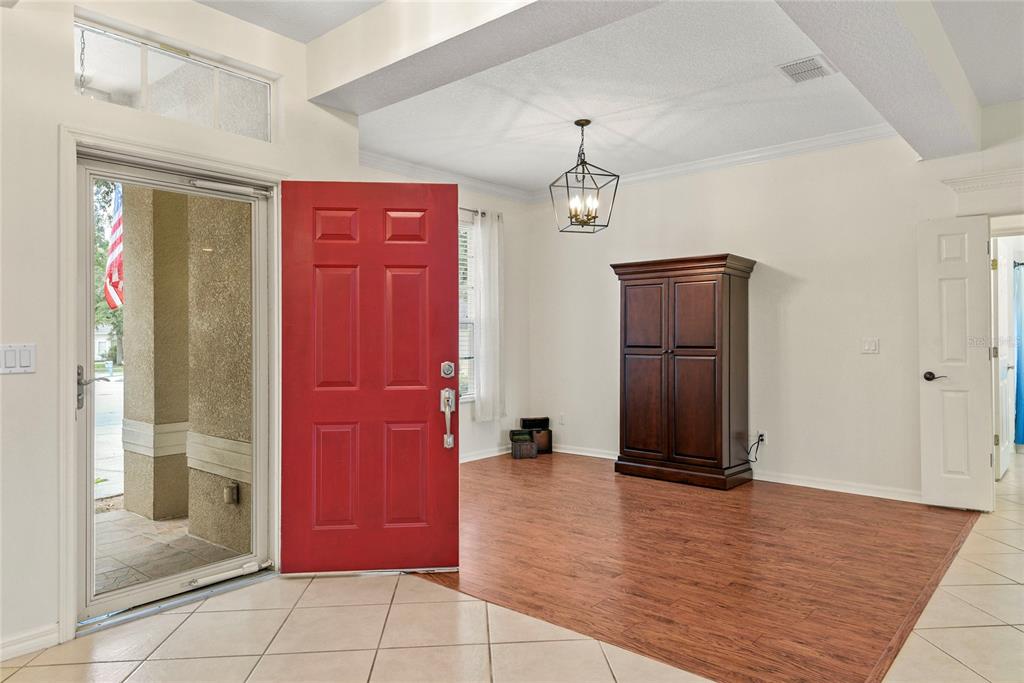 An entryway with a red front door, wood flooring, and a dark wood armoire — 1500 LUCKY PENNIE WAY, APOPKA, FL