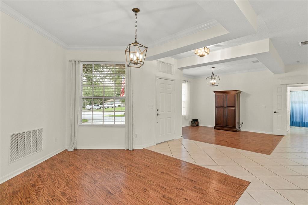 A room with wood-look flooring, tile entryway, white walls, and two hanging light fixtures — 1500 LUCKY PENNIE WAY, APOPKA, FL