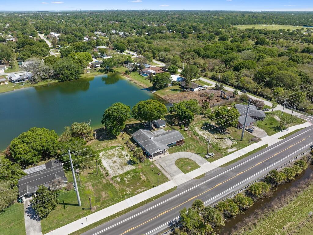 An aerial view shows houses along a road next to a pond and wooded area — 6208 Emerson Avenue, Fort Pierce FL 34951, FORT PIERCE, FL