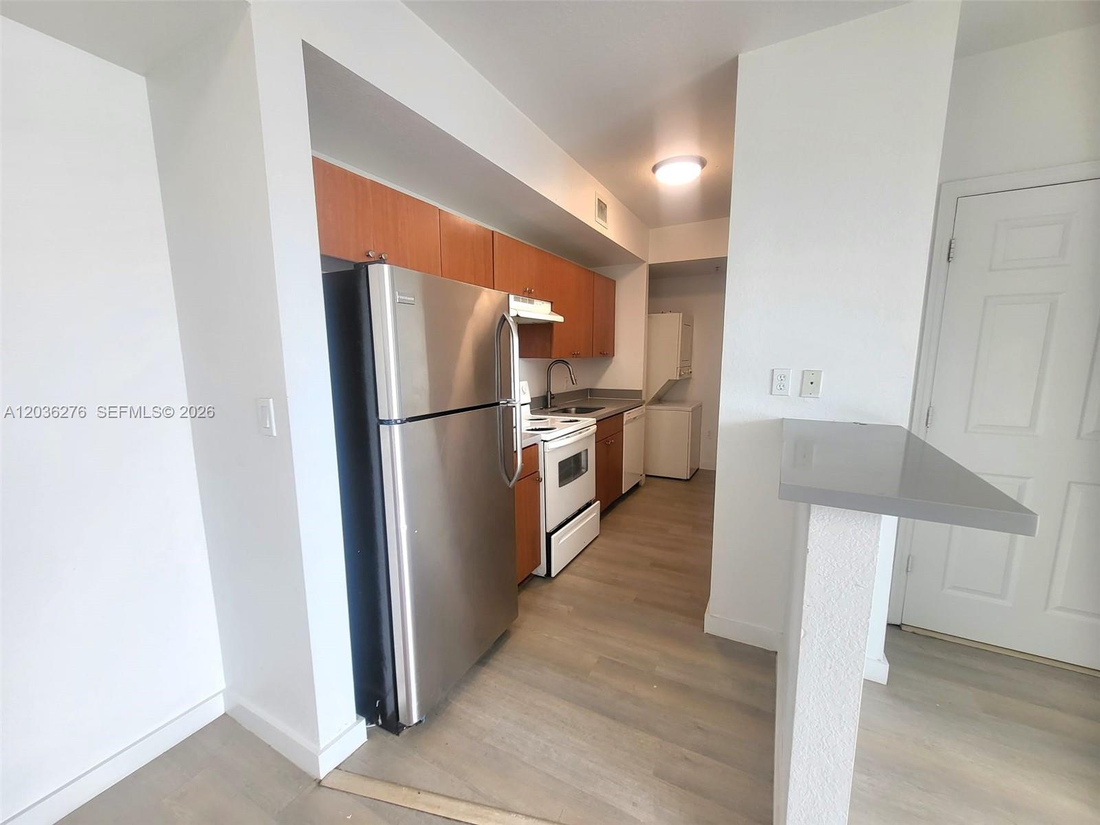 A kitchen features stainless steel appliances, wood cabinets, and light-colored wood-look flooring — 120 SW 8th Ave # 703, Miami FL 33130, MIAMI, FL