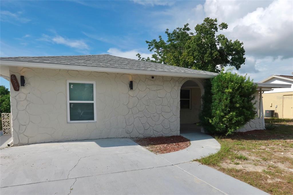 A single-story house with a textured stone facade, a concrete driveway, and a covered entryway — 6533 RIDGE CREST DRIVE, PORT RICHEY, FL