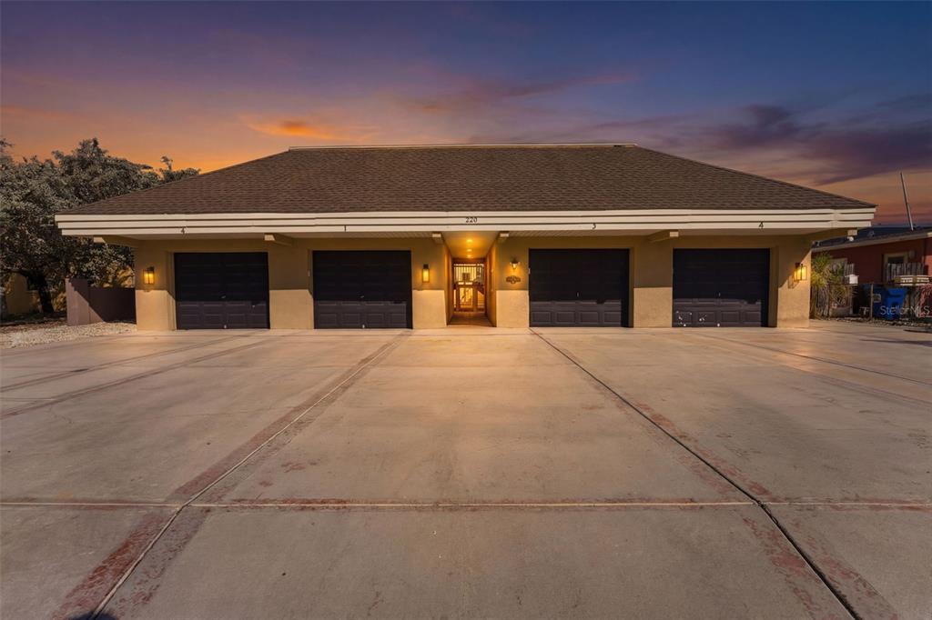 A low-rise building features four garage doors and a central entryway under a wide roof — 220 126TH AVENUE UNIT 1, TREASURE ISLAND, FL