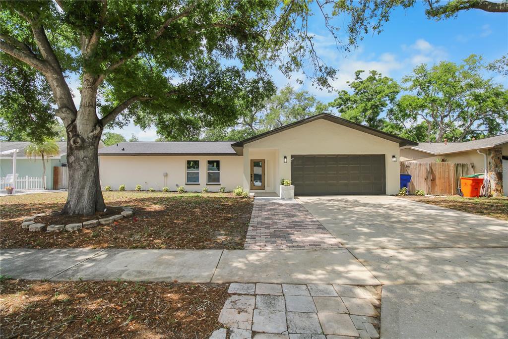 A single-story house with a beige exterior, dark garage door, and a brick walkway — 11492 93RD STREET, LARGO, FL