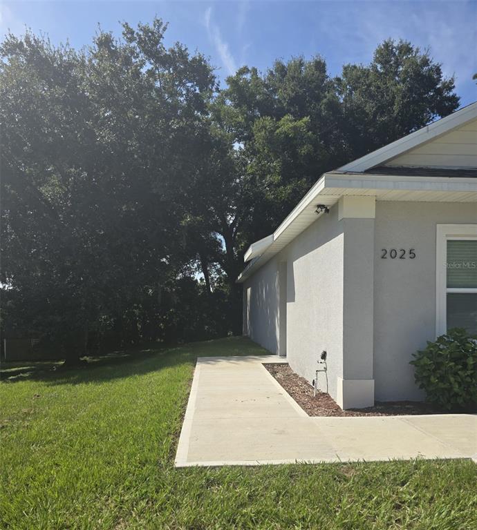 A concrete walkway runs along the side of a gray house with a grassy yard — 2025 DUNBAR ST UNIT 2025, BARTOW, FL