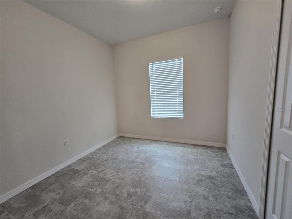 An empty room with light-colored walls, a single window with blinds, and gray tile flooring — 2025 DUNBAR ST UNIT 2025, BARTOW, FL