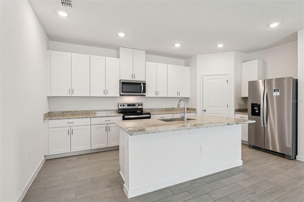 A kitchen featuring white cabinets, granite countertops, stainless steel appliances, and a central island — 71 WANDERING CREEK WAY, PALM COAST, FL