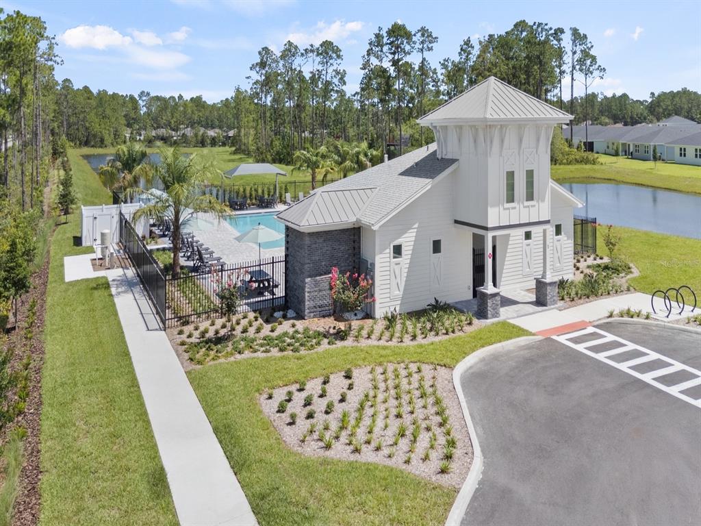 An aerial view of a community clubhouse with a swimming pool and surrounding pond — 71 WANDERING CREEK WAY, PALM COAST, FL
