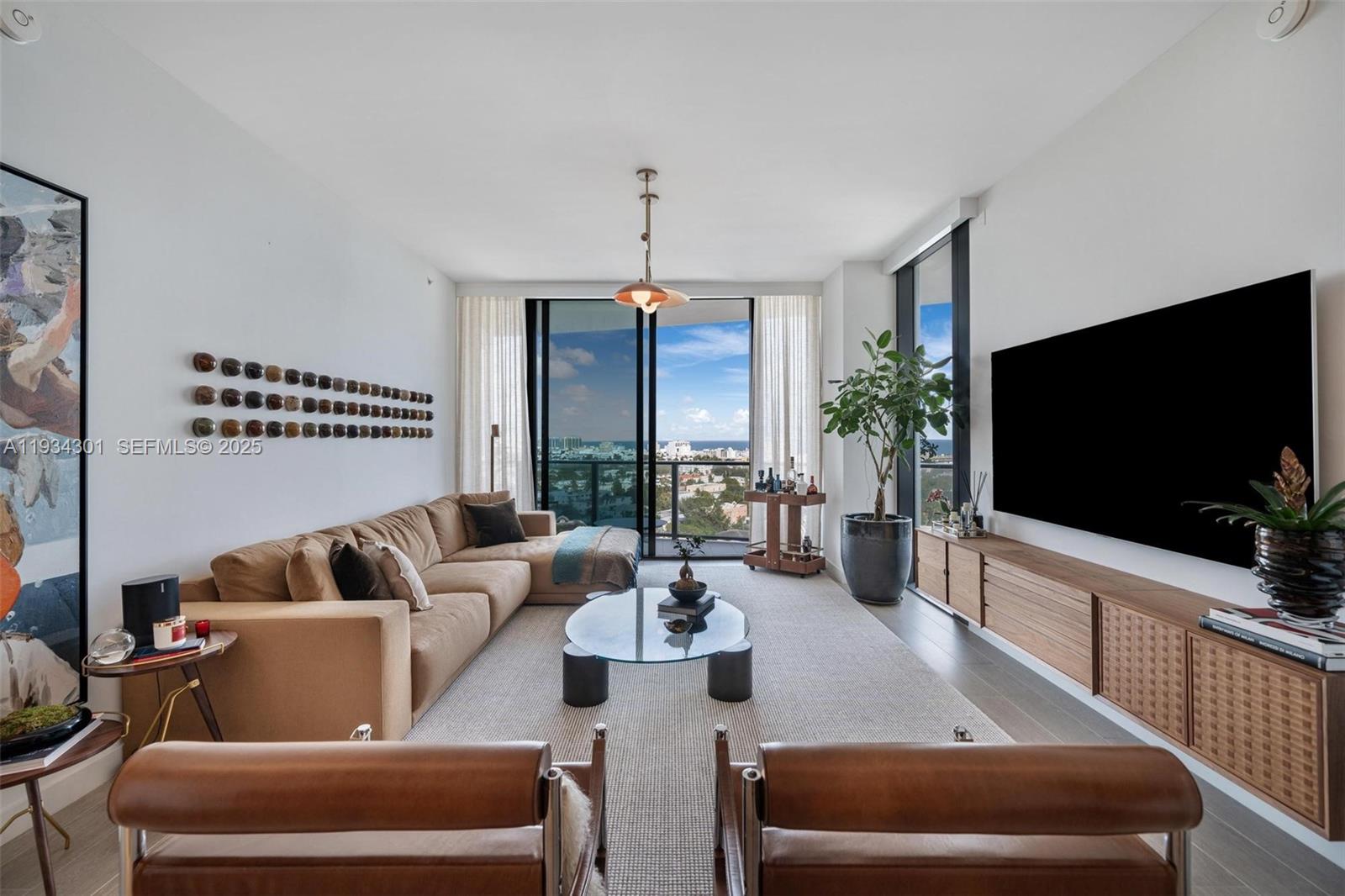 A modern living room features a tan sectional sofa, leather chairs, and a large balcony view — 500 Alton Rd # 1602, Miami Beach FL 33139, MIAMI BEACH, FL