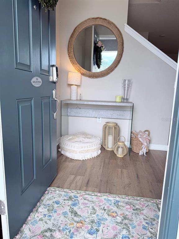 An entryway features a blue door, a console table, a round mirror, and wood flooring — 380 HUCKLEBERRY BLOSSOM DRIVE, ST CLOUD, FL