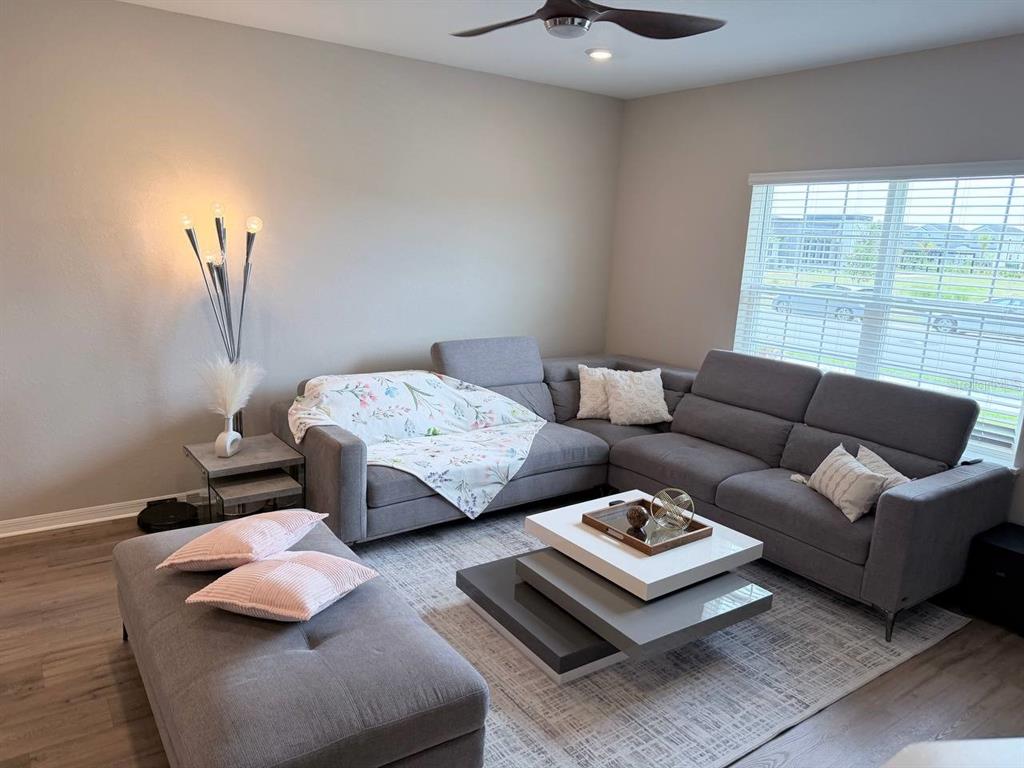A living room features a gray sectional sofa, a tiered coffee table, and a floor lamp — 380 HUCKLEBERRY BLOSSOM DRIVE, ST CLOUD, FL