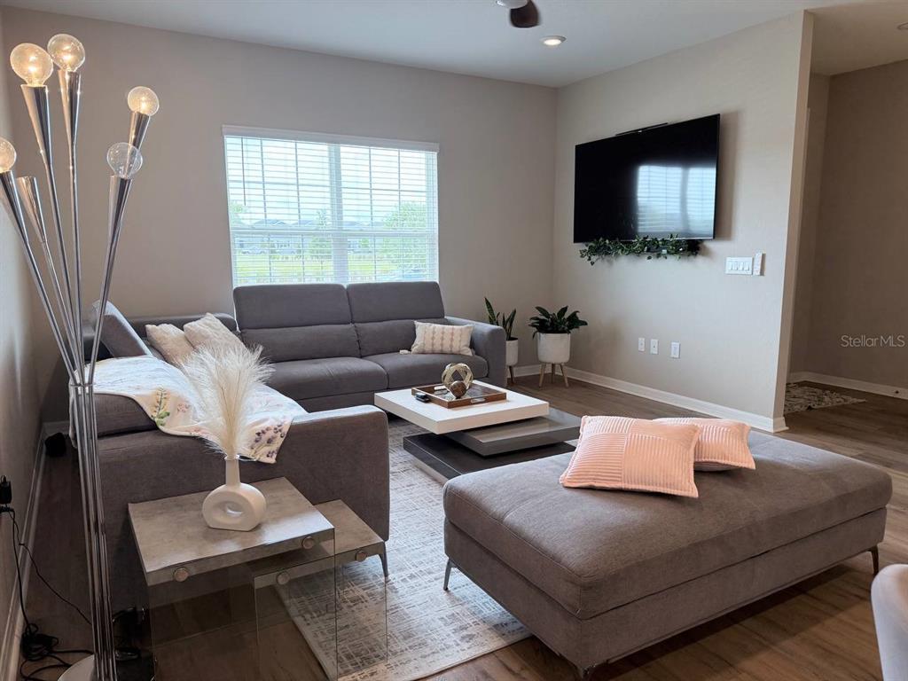 A living room features a gray sectional sofa, a large ottoman, and a wall-mounted television — 380 HUCKLEBERRY BLOSSOM DRIVE, ST CLOUD, FL