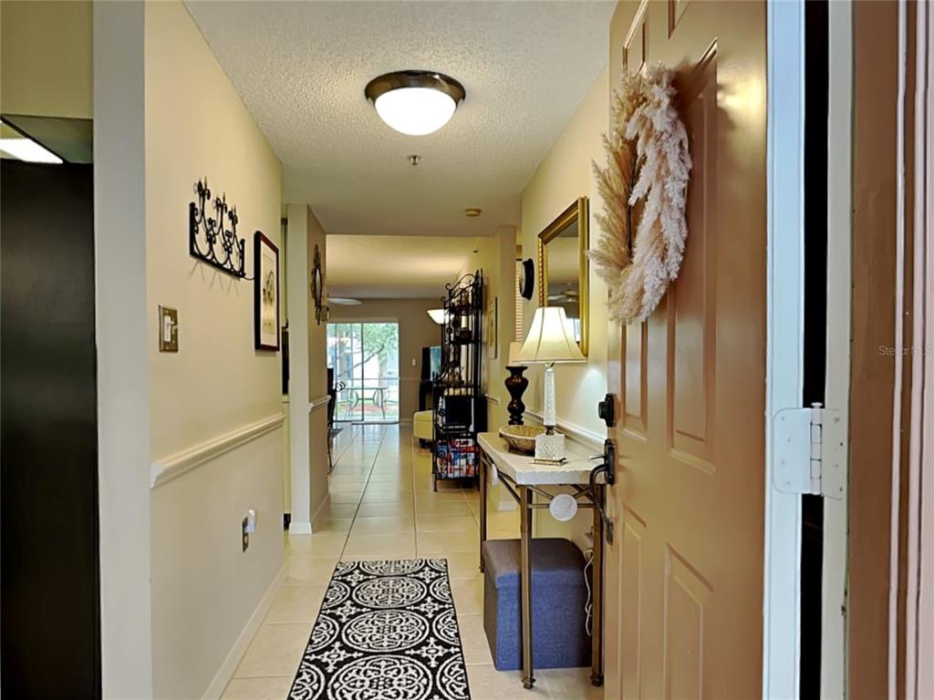 An entryway with tile flooring leads into a living area with a sliding glass door — 6501 STONE RIVER ROAD UNIT 110, BRADENTON, FL