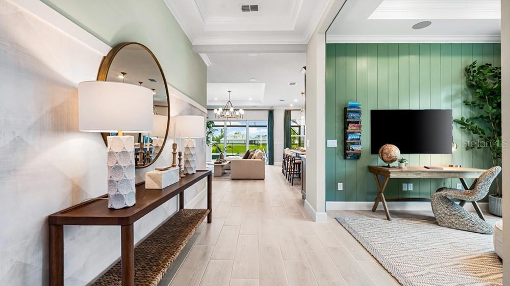 A hallway leads to a living area, featuring a console table, desk, and green walls — 11221 CARDING MILL LANE, WINTER GARDEN, FL