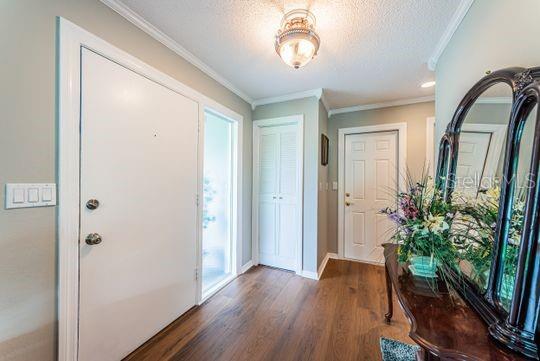 A bright entryway features wood floors, a white door, a closet, and a decorative mirror — 4577 GREAT LAKES DRIVE S UNIT 1, CLEARWATER, FL