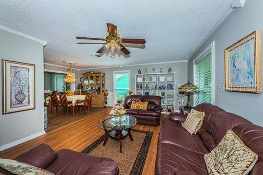 A living room with brown leather sofas, a glass coffee table, and an adjacent dining area — 4577 GREAT LAKES DRIVE S UNIT 1, CLEARWATER, FL