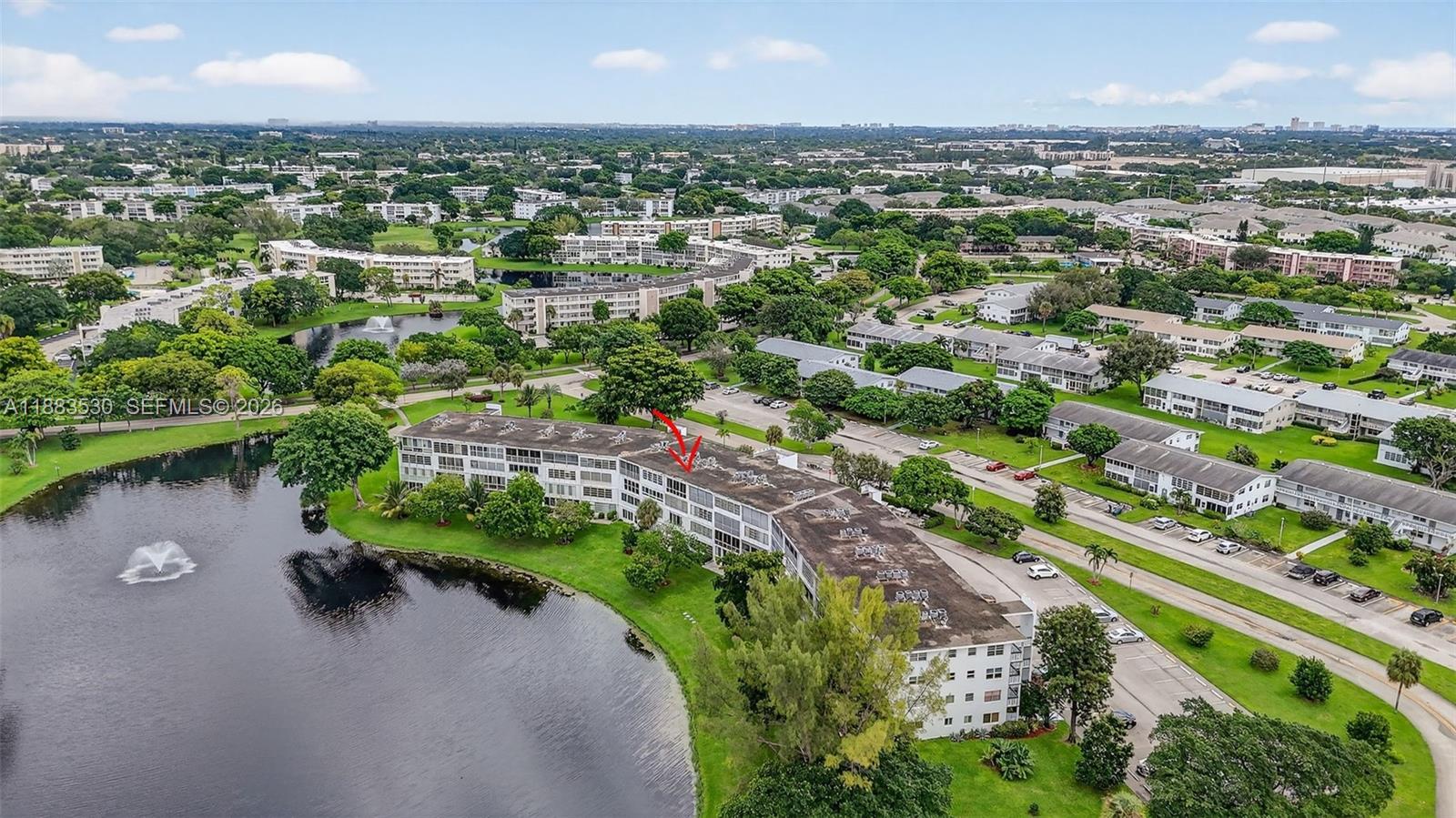 An aerial view shows a multi-story apartment building situated next to a lake — 2009 N Farnham  N # 2009, Deerfield Beach FL 33442, DEERFIELD BEACH, FL