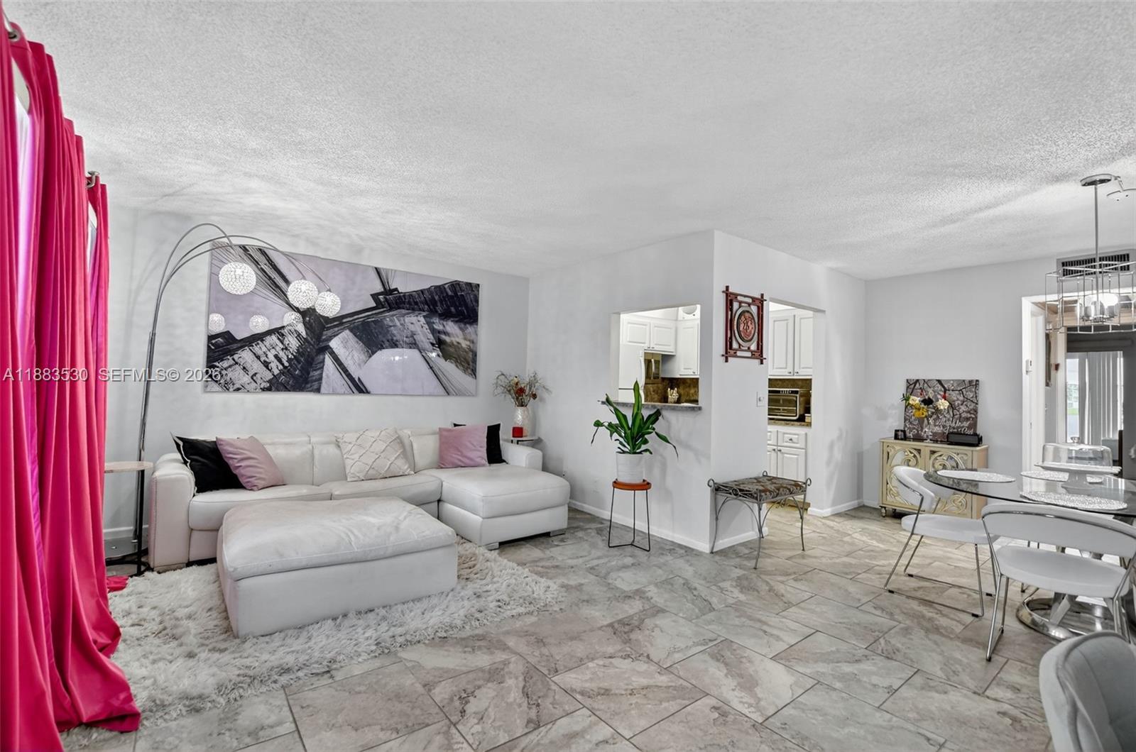 A living room with a white sectional sofa, tile floors, and an adjacent dining area — 2009 N Farnham  N # 2009, Deerfield Beach FL 33442, DEERFIELD BEACH, FL