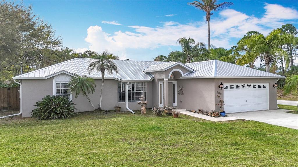 A single-story house with a light gray exterior, a metal roof, and a two-car garage — 2686 SW FAIRGREEN ROAD, PORT ST LUCIE, FL