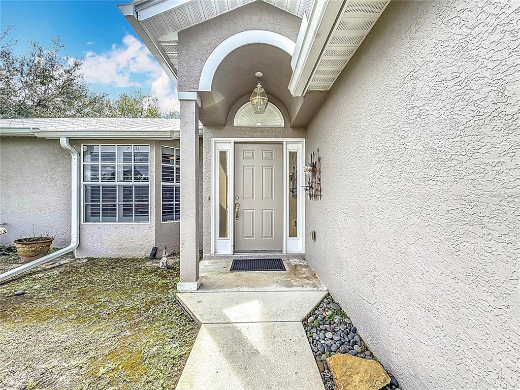 The exterior entrance features a beige front door, a concrete walkway, and a stucco facade — 2686 SW FAIRGREEN ROAD, PORT ST LUCIE, FL