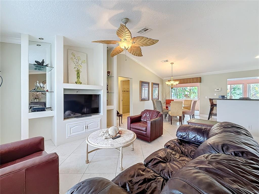 A living room features a leather sofa, two armchairs, a coffee table, and built-in shelving — 2686 SW FAIRGREEN ROAD, PORT ST LUCIE, FL