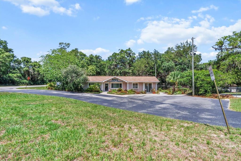 A single-story commercial building with a paved parking lot sits surrounded by trees — 2716 S LECANTO HIGHWAY, LECANTO, FL