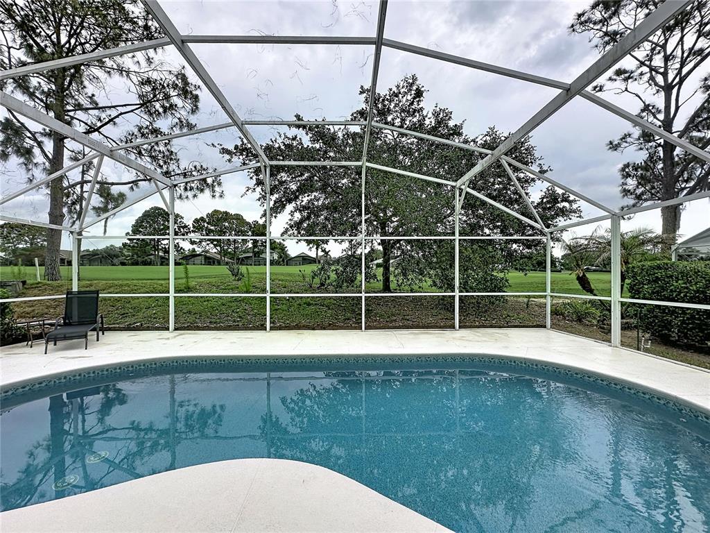 A swimming pool is enclosed by a screened lanai overlooking a grassy golf course — 1529 GULF VUE DRIVE, HAINES CITY, FL