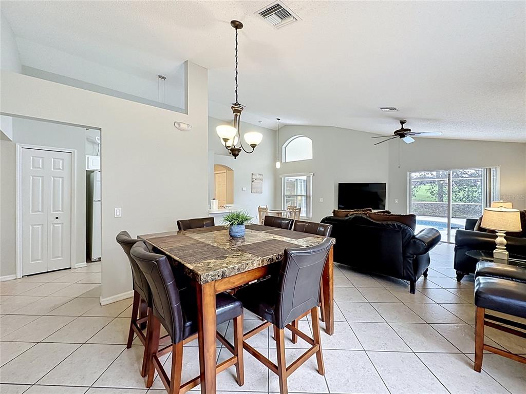 A dining area with a square stone-topped table and chairs opens into a living room — 1529 GULF VUE DRIVE, HAINES CITY, FL