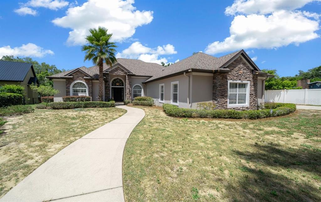 A single-story house with a stone facade, a concrete walkway, and a palm tree — 1251 MAGNOLIA FARMS COURT, EUSTIS, FL