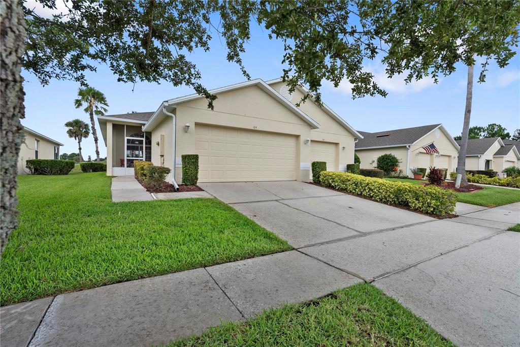 A beige single-story house with a two-car garage and a screened front entryway — 104 CLUB VILLAS LANE UNIT N/A, KISSIMMEE, FL