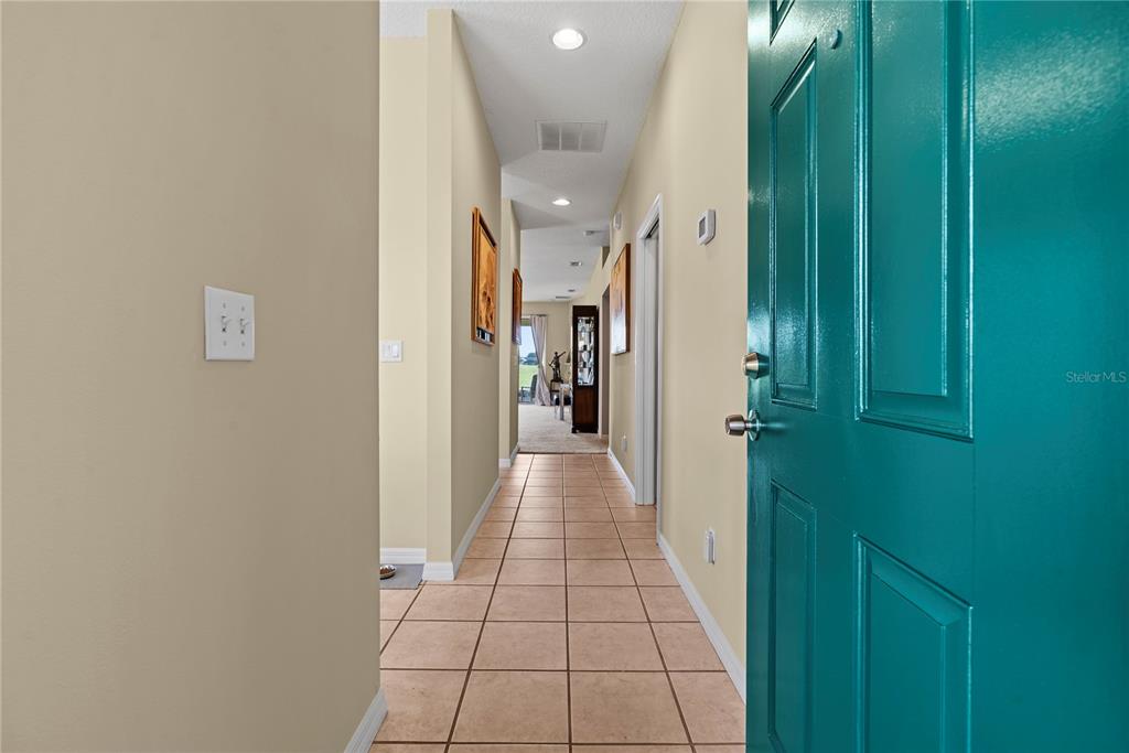 A teal front door opens into a tiled hallway leading toward a sunlit living area — 104 CLUB VILLAS LANE UNIT N/A, KISSIMMEE, FL