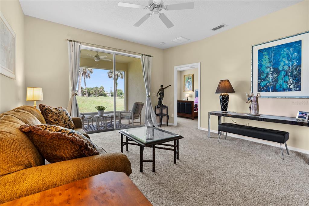 A living room features a tan sofa, glass coffee table, and sliding doors to a patio — 104 CLUB VILLAS LANE UNIT N/A, KISSIMMEE, FL