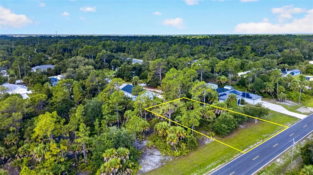 An aerial view shows a vacant, tree-covered residential lot outlined in yellow next to a road — 18303 HILLSBOROUGH BOULEVARD, PORT CHARLOTTE, FL