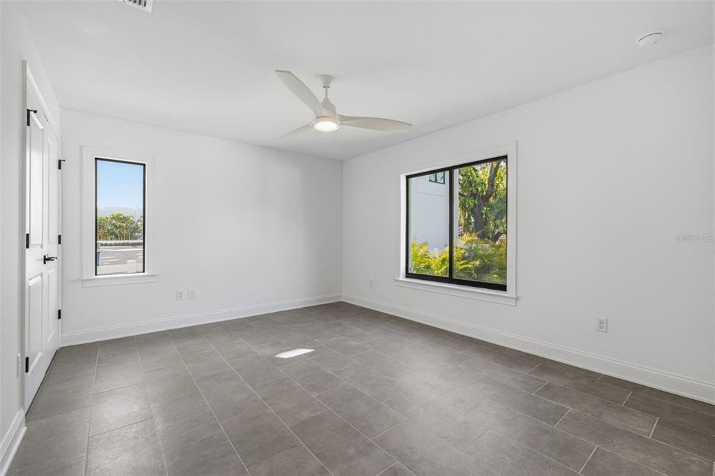 An empty bedroom features white walls, gray tile flooring, a ceiling fan, and two windows — 4509 W NORTH A STREET UNIT 2, TAMPA, FL