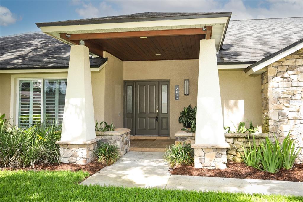 A house exterior features a covered entryway with stone-based pillars and a dark front door — 280 W SPRING LAKE DRIVE, ALTAMONTE SPRINGS, FL