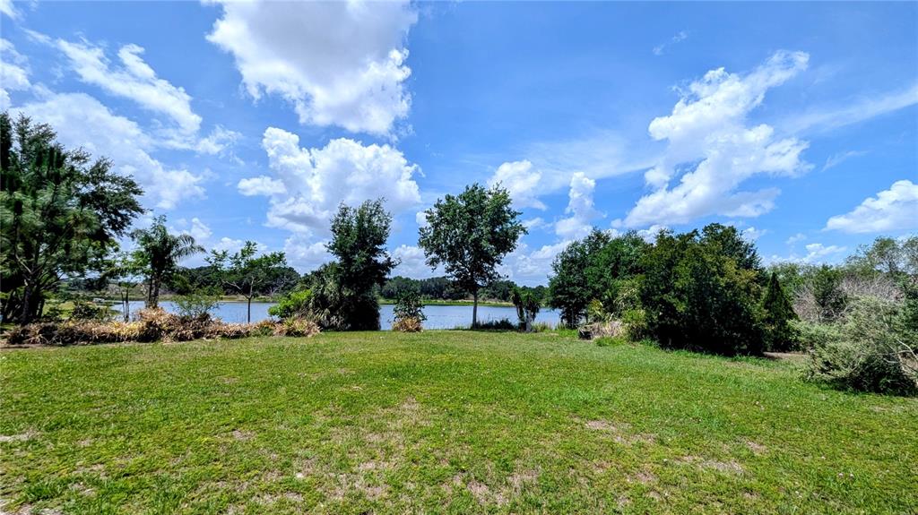 A grassy lawn leads to a lake surrounded by trees under a blue sky — 1100 PENINSULAR DRIVE, LAKE WALES, FL