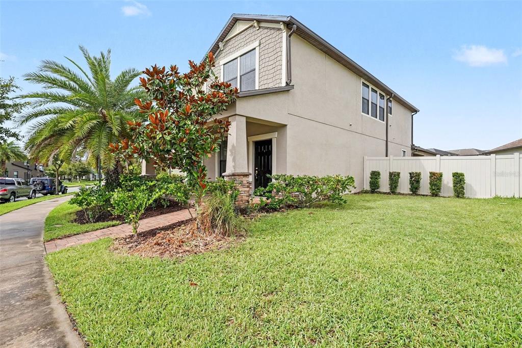 A two-story house with a tan stucco exterior, a front porch, and a grassy yard — 28500 PLEASANT BAY LOOP, WESLEY CHAPEL, FL