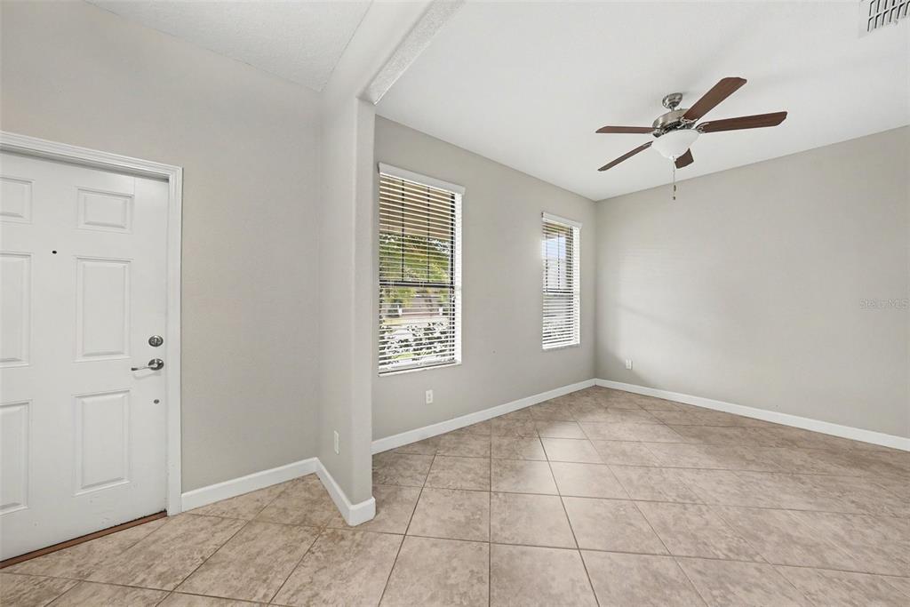 An empty room with light gray walls, tile flooring, two windows, and a ceiling fan — 28500 PLEASANT BAY LOOP, WESLEY CHAPEL, FL