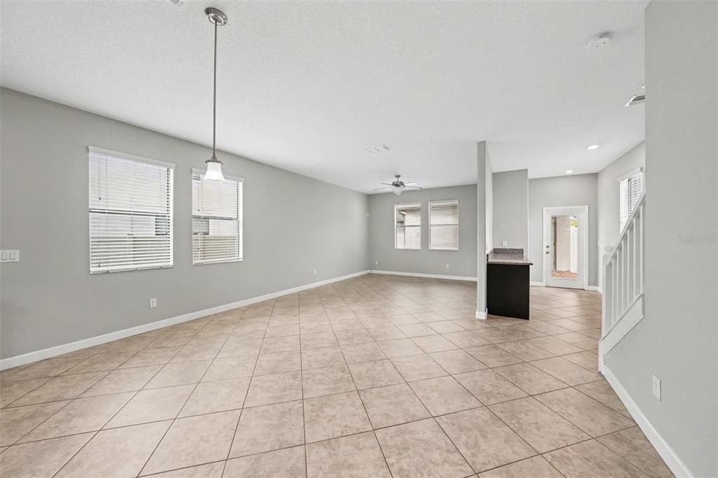 An open-concept living area features light gray walls, tile flooring, and a staircase — 28500 PLEASANT BAY LOOP, WESLEY CHAPEL, FL