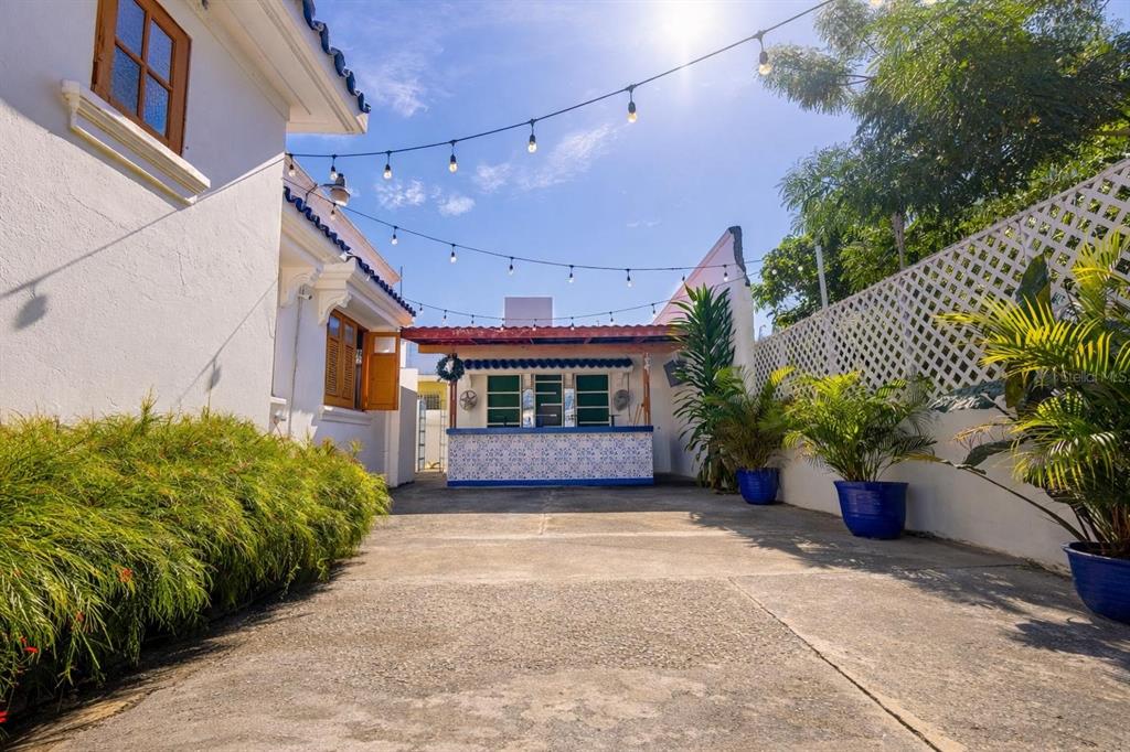 A paved outdoor patio features a tiled bar, string lights, and potted plants — 70 Calle DEL BOSQUE, MAYAGUEZ, PR