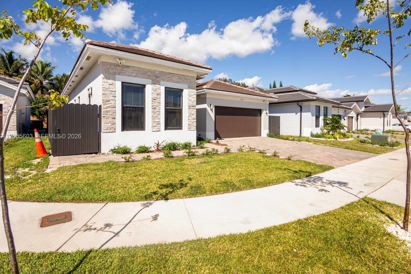 A single-story house with a stone facade, brown garage door, and a paved driveway — 19452 SW 124th Ct # 0, Miami FL 33177, MIAMI, FL