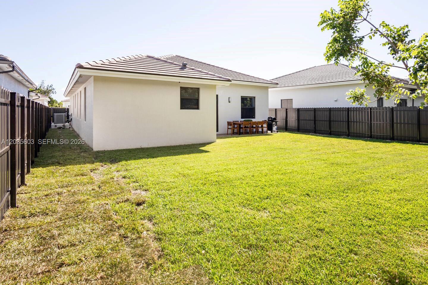 The backyard features a grassy lawn, a patio with outdoor furniture, and dark privacy fencing — 19452 SW 124th Ct # 0, Miami FL 33177, MIAMI, FL