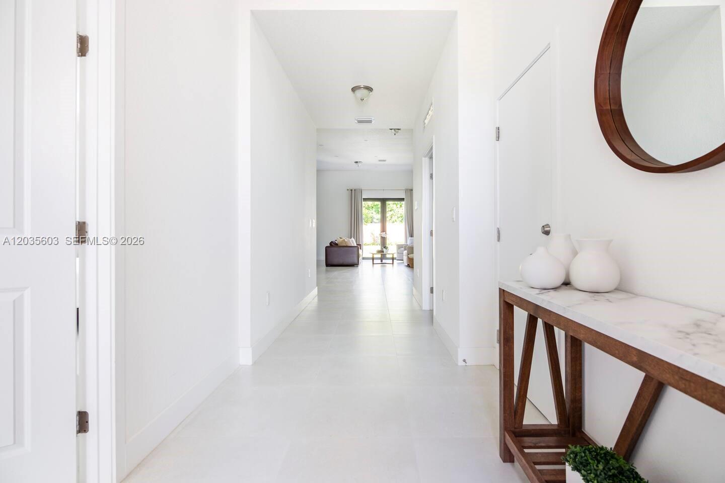 A bright, white-walled hallway leads to a living area with tile flooring and a console — 19452 SW 124th Ct # 0, Miami FL 33177, MIAMI, FL