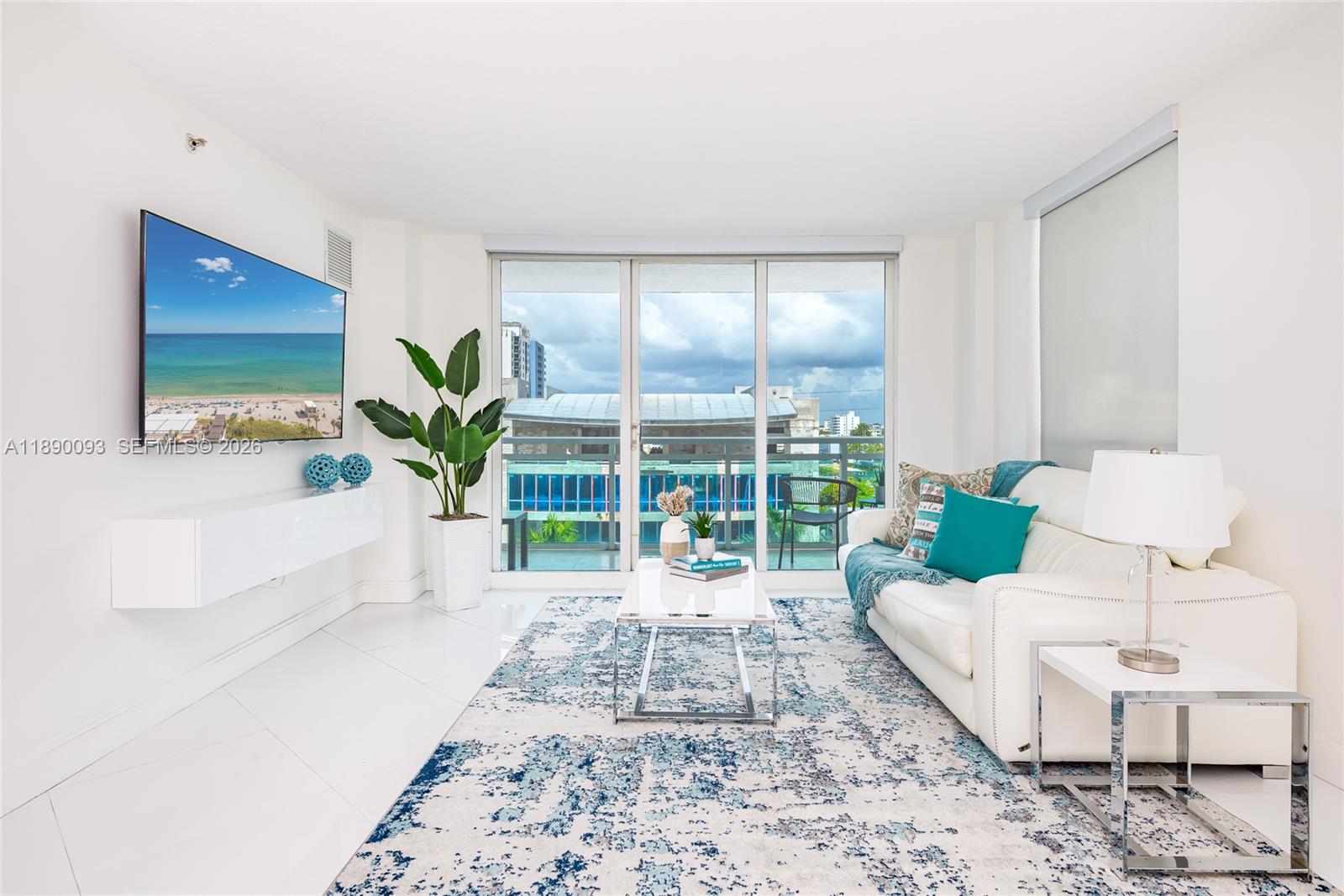A modern living room features a white sofa, a patterned rug, and a wall-mounted television — 6917 Collins Ave # 720, Miami Beach FL 33141, MIAMI BEACH, FL