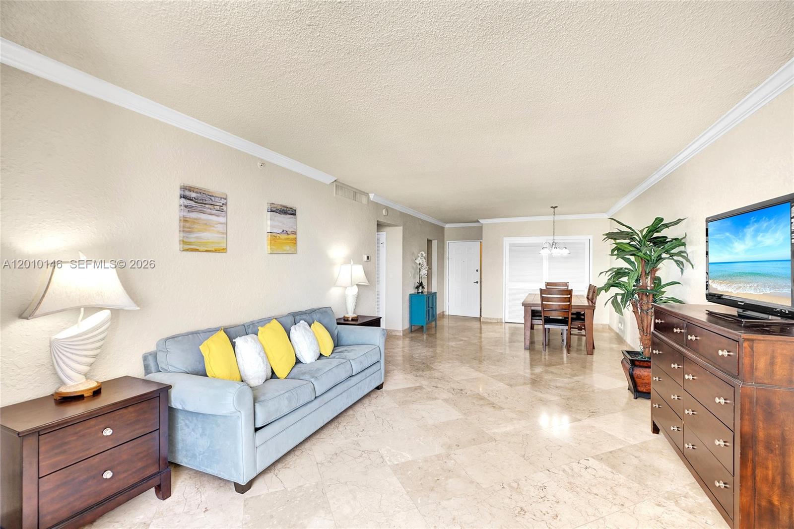 A living and dining area features tile floors, a blue sofa, and a wooden dresser — 2501 S Ocean Dr # 414, Hollywood FL 33019, HOLLYWOOD, FL