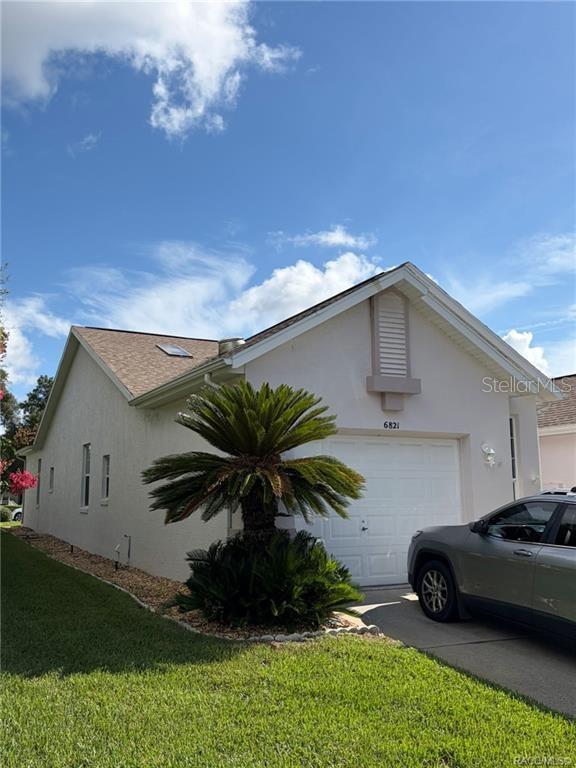 A single-story house with a white stucco exterior, a garage, and a large palm tree — 6821 E QUEENSBURY LANE, INVERNESS, FL