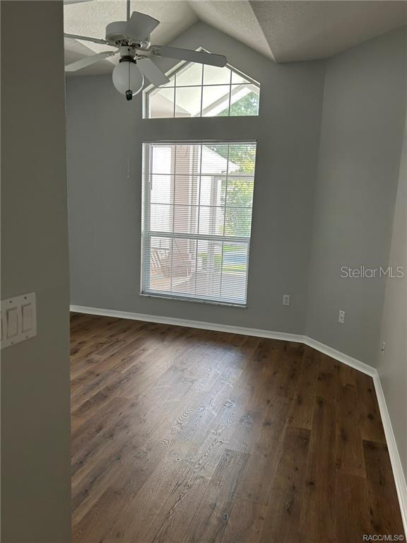 An empty room features wood-look flooring, light gray walls, a ceiling fan, and a large window — 6821 E QUEENSBURY LANE, INVERNESS, FL