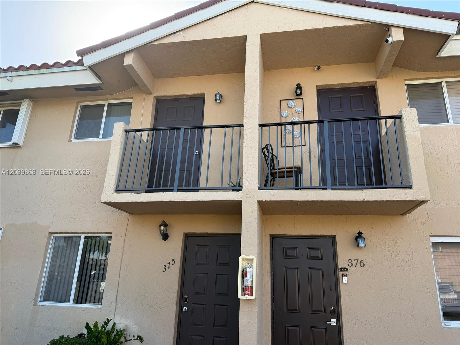 The exterior of a two-story apartment building features brown doors, balconies, and stucco walls — 541 NW 82nd Ct # 375, Miami FL 33126, MIAMI, FL
